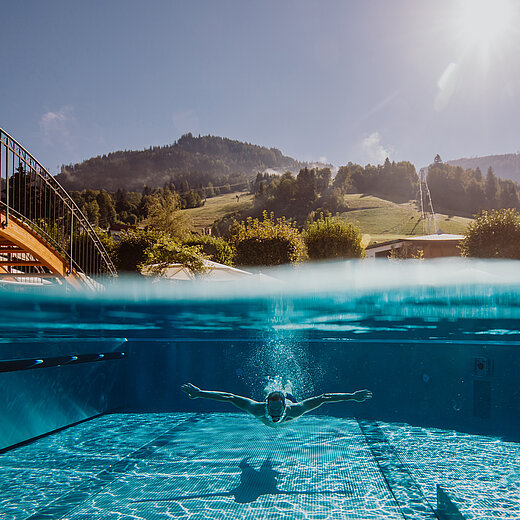 Mann beim Tauchen im Outdoor Pool im Wellnesshotel Berghof
