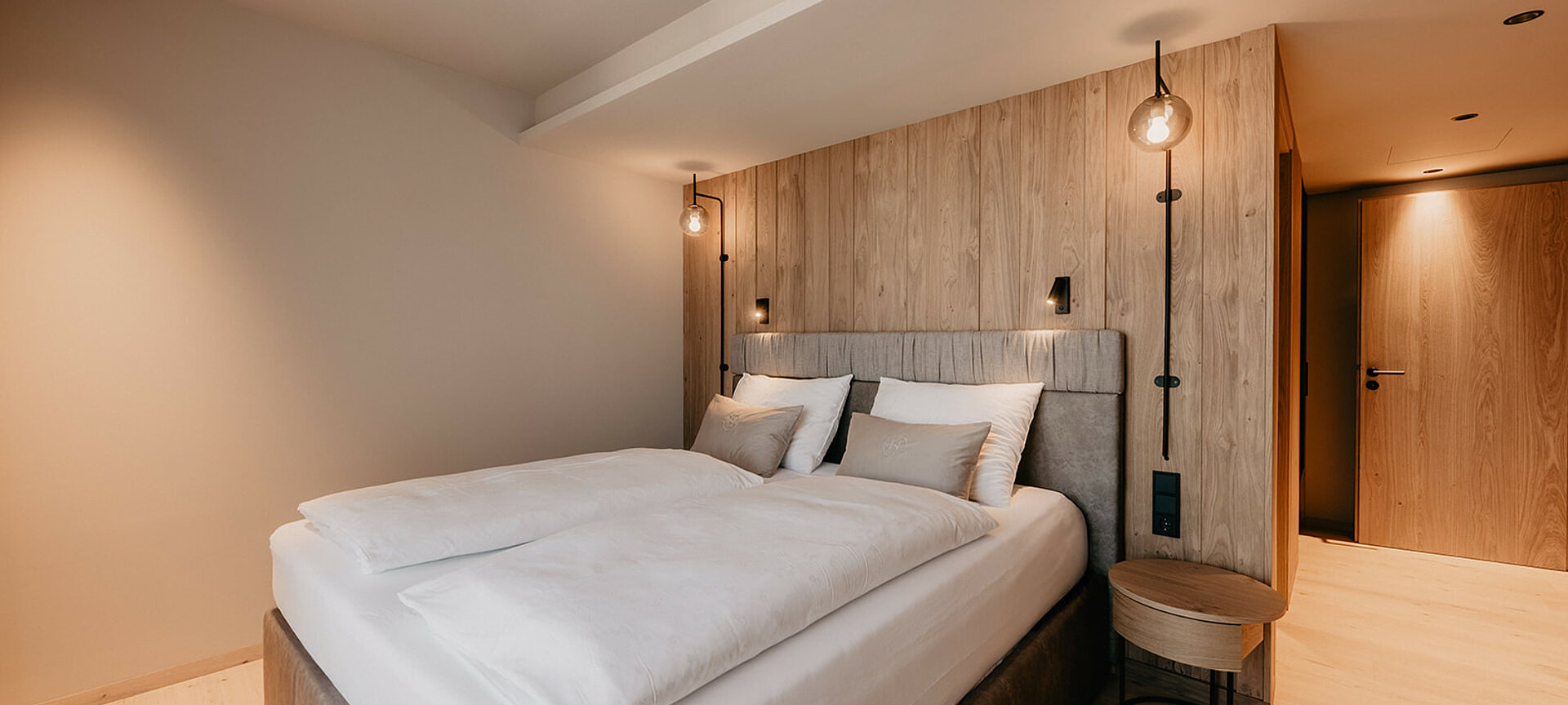 Zweites Schlafzimmer der Berghof Suite Premium mit modernem Boxspringbett und natürlicher Holzverkleidung im Hotel Berghof Salzburg.